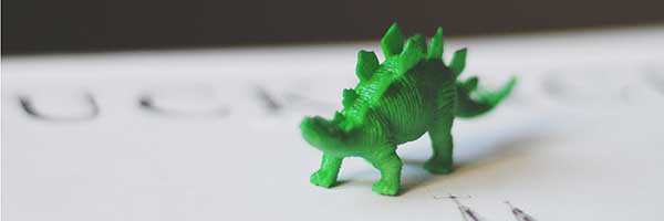 green dinosaur figurine on college desk